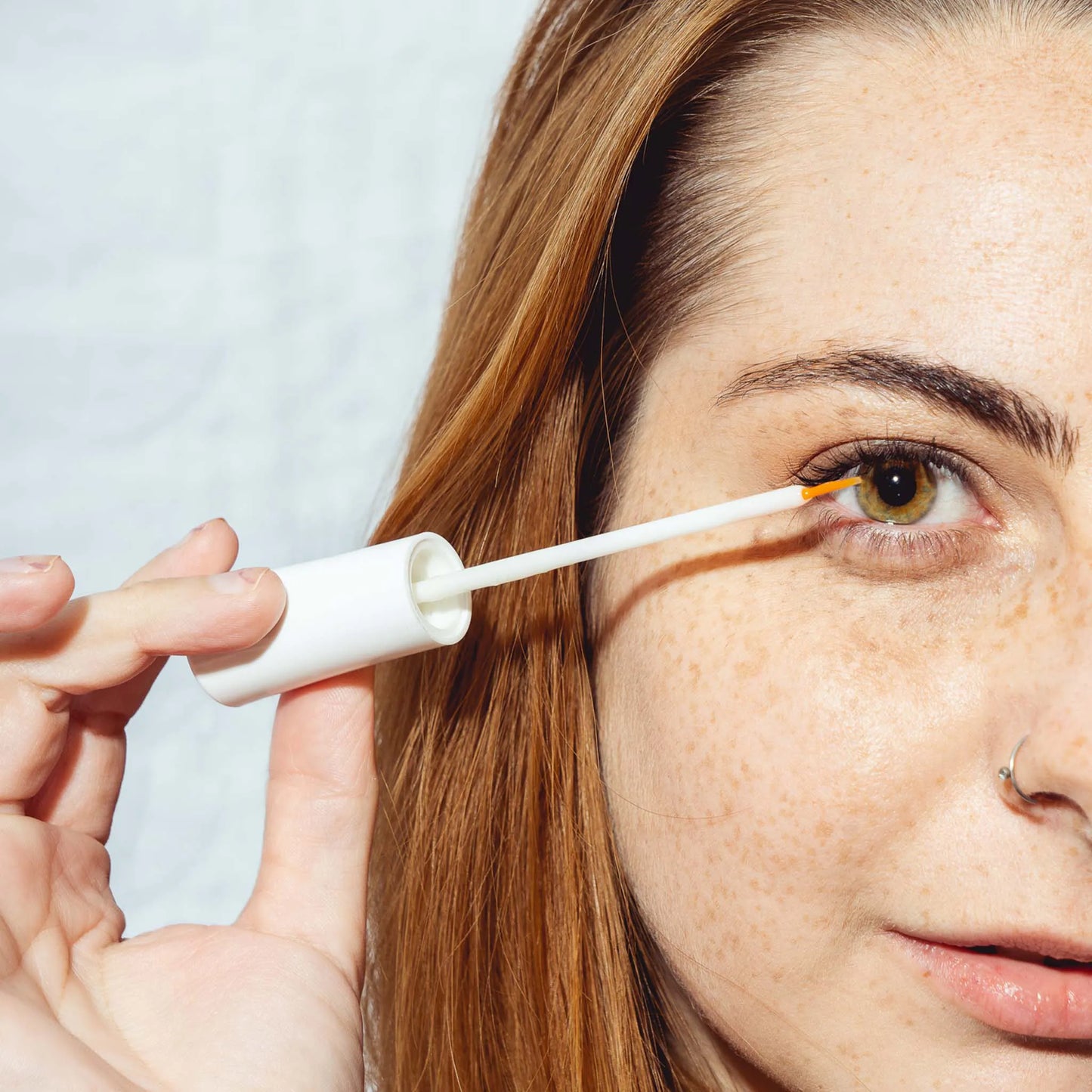 a woman holds the serum in front of her eye