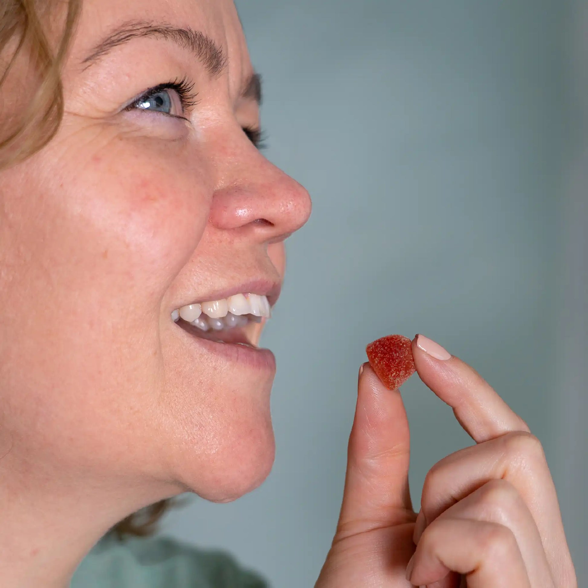 A woman takes a CBD gummy from Nordic Oil