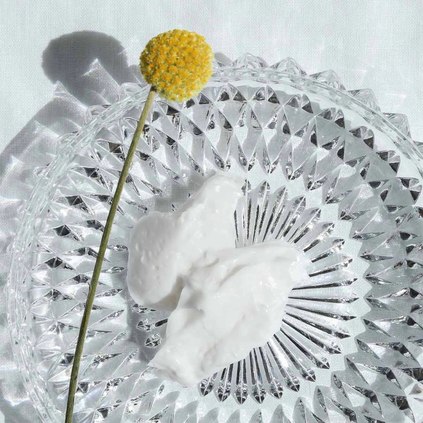 the cream is in a bowl and a yellow flower lays on to of it