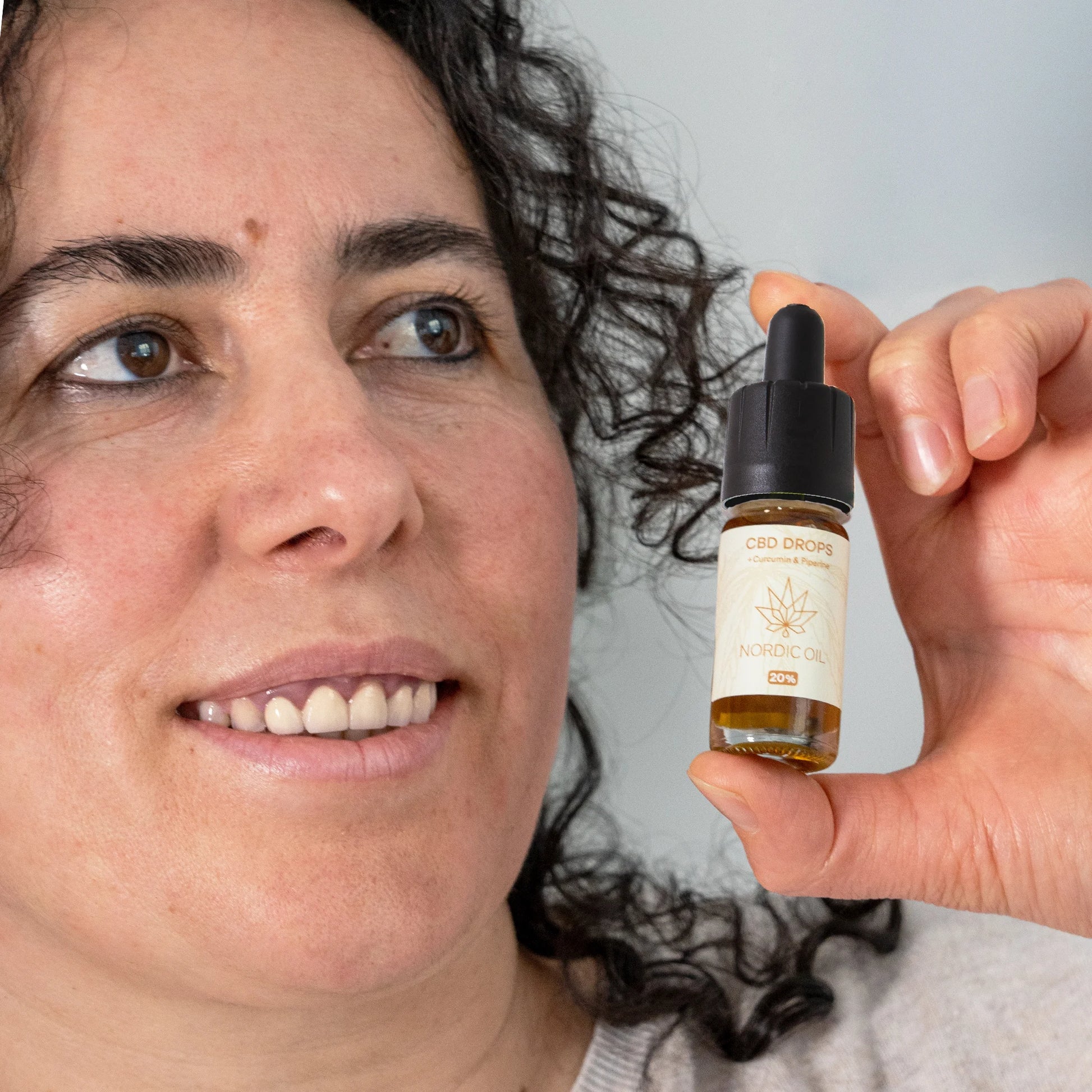 woman holding nordic oil cbd drops with curcmin bottle