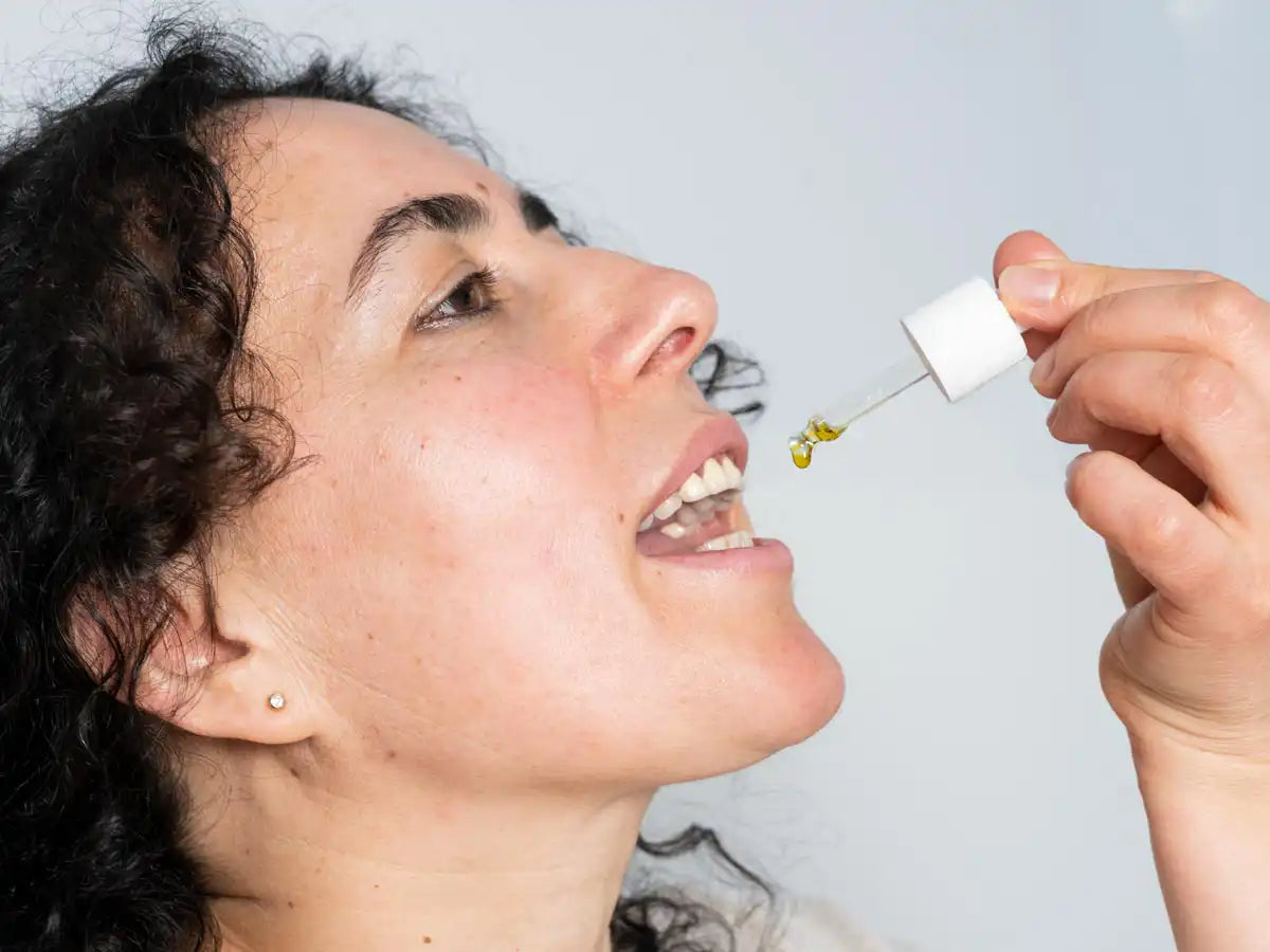 Woman drops some CBD Oil into her mouth