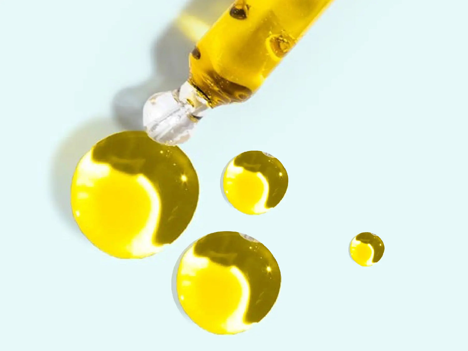 Pipette and oil drops showing the golden color of the CBD oil