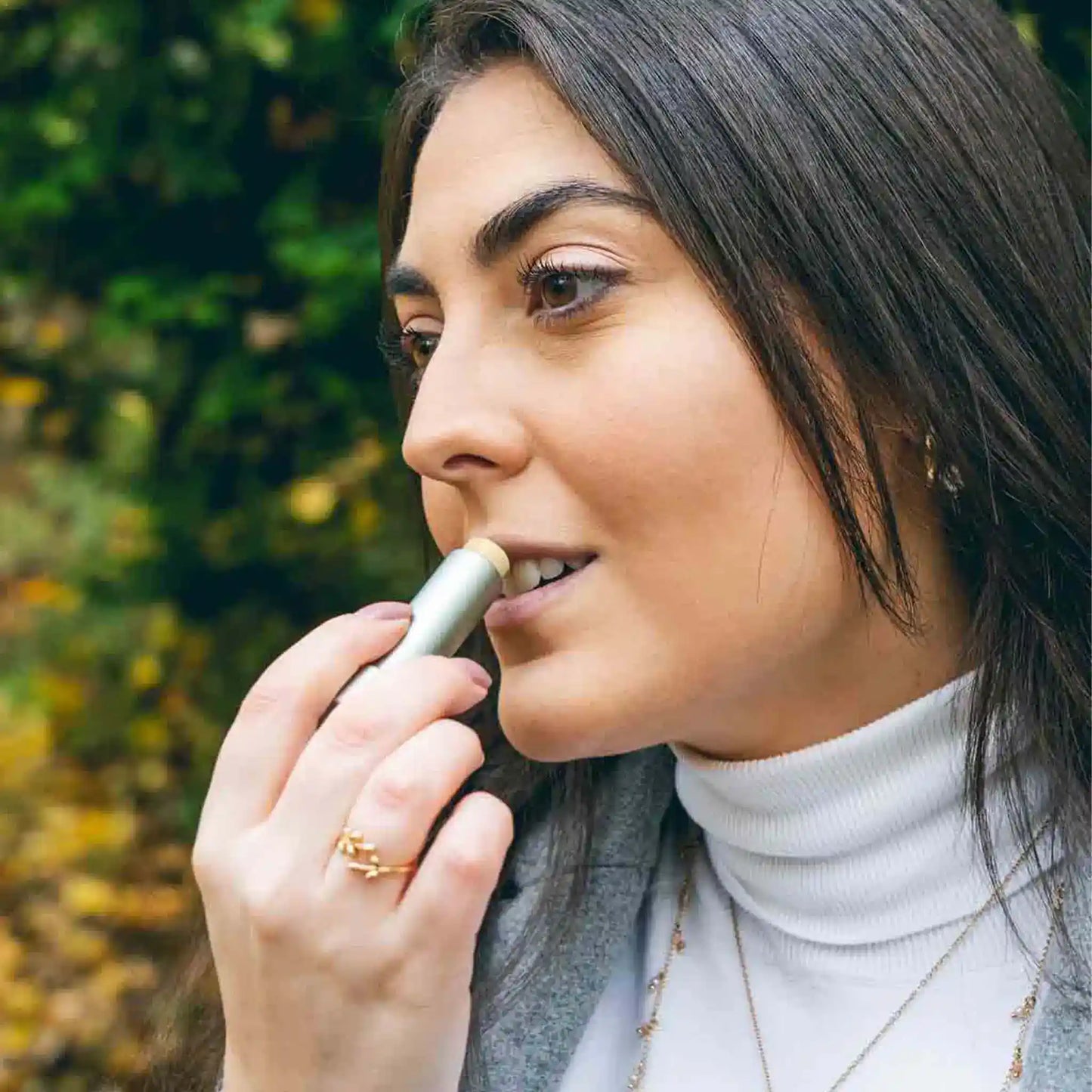 A woman applies CBD lip balm to her lips.